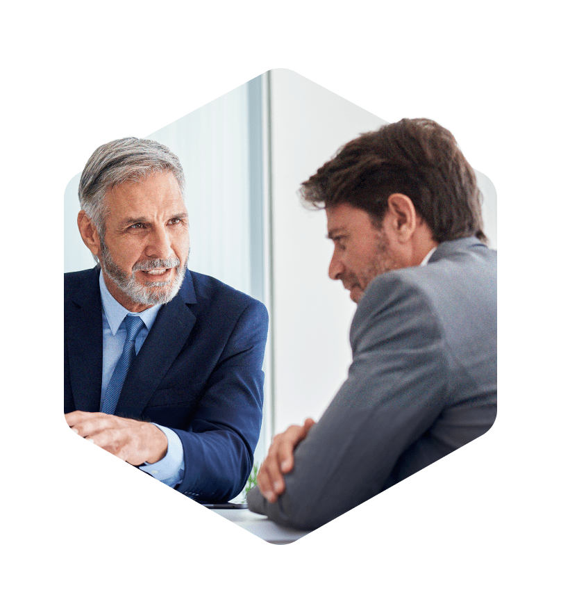 A photo masked in a hexagon of two male business professionals in conversation