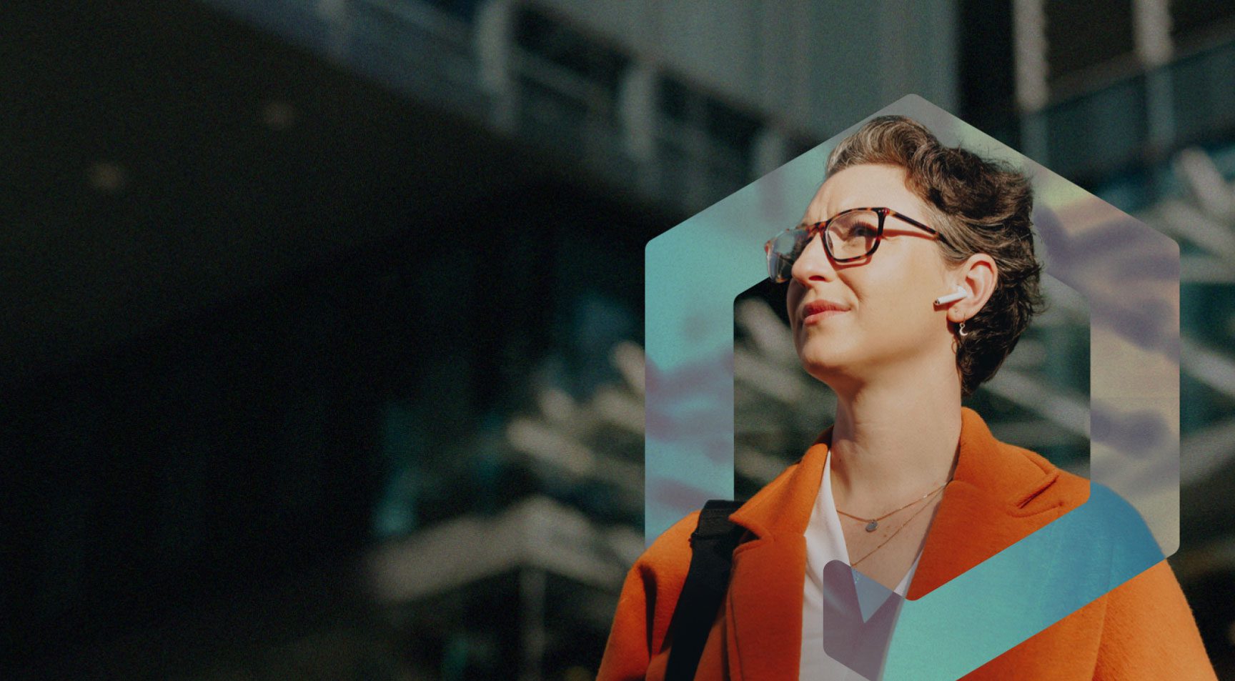 Warm photo of a professional woman with glasses, outdoors looking off into the distance with confidence framed in the Priority Commerce mark