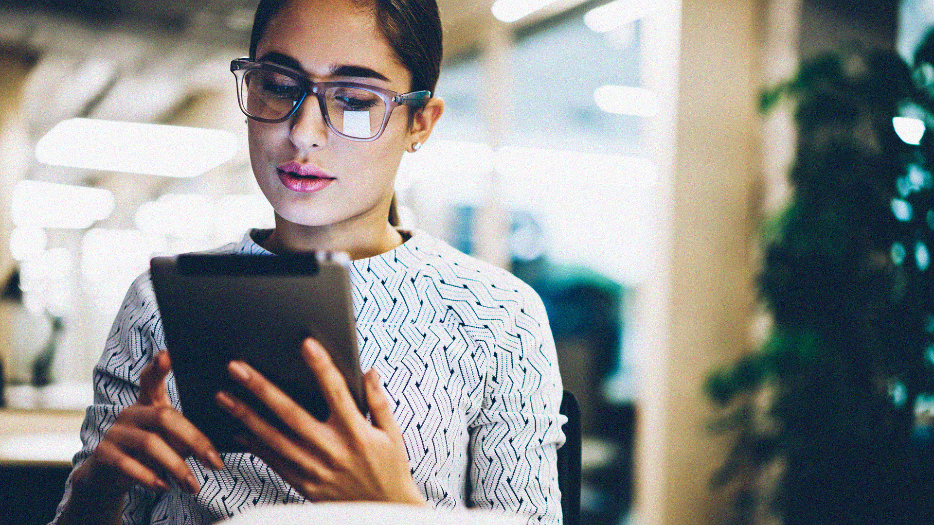 Woman with glasses reading ipad with glare in glasses