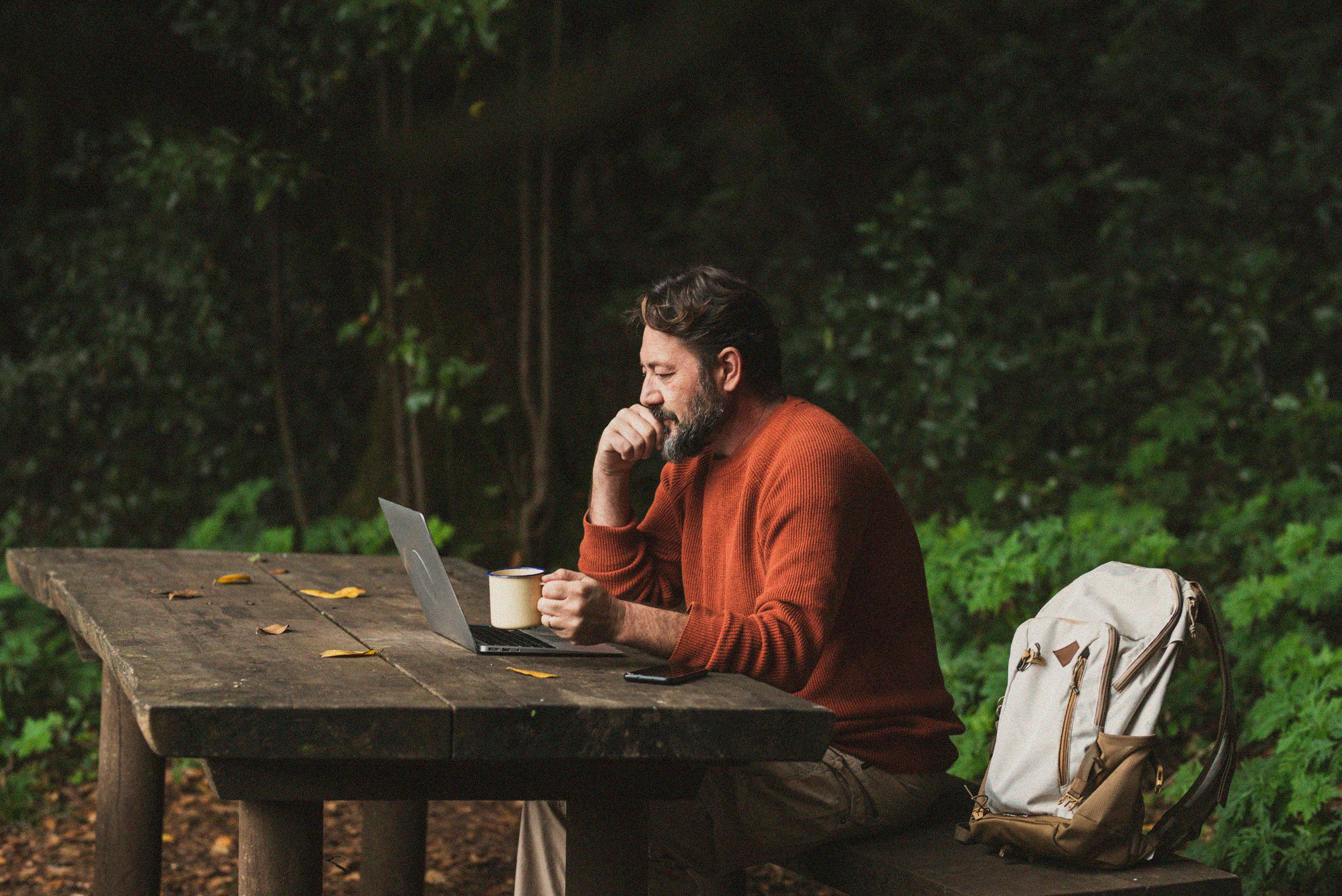 Man outdoors focused yet leisurely working on laptop