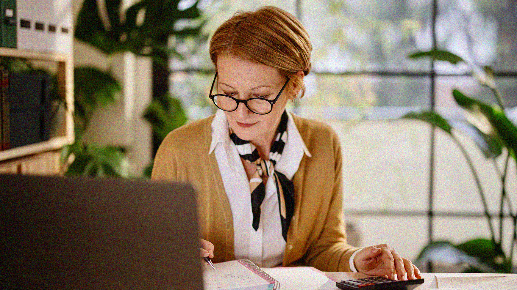 Woman analyzing financials at computer with calculator