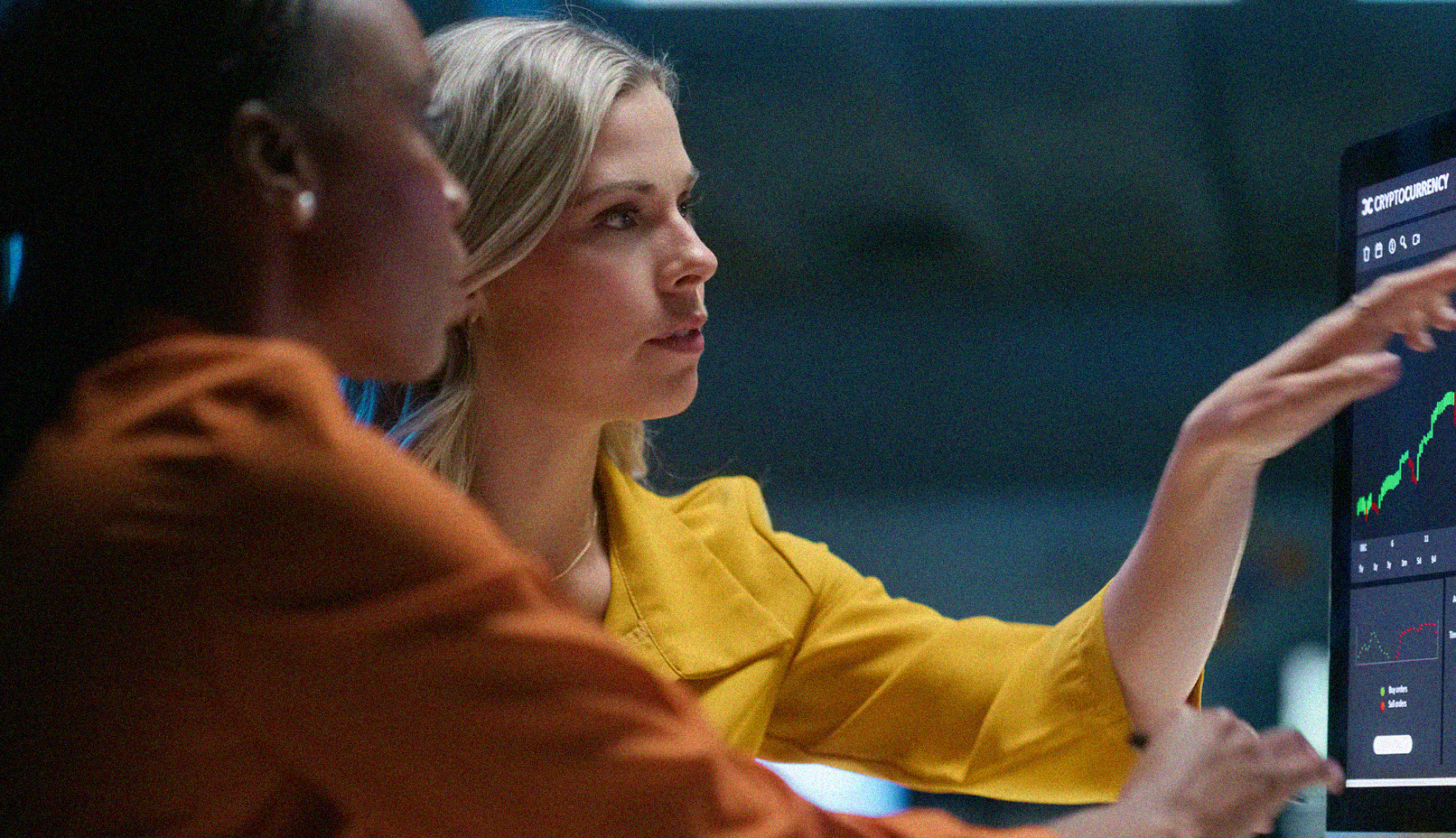 Close up of two women discussing graphs on a screen