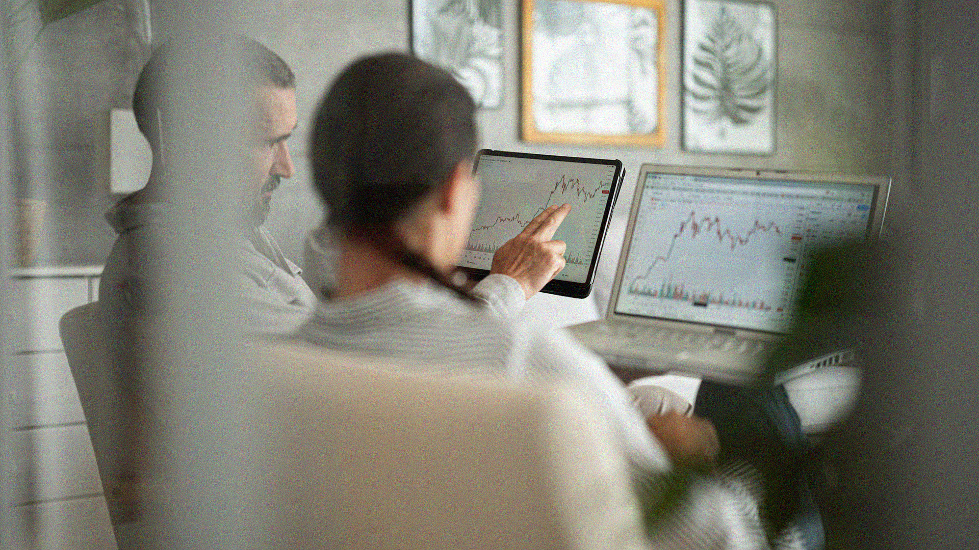 Candid view of two people assessing line graphs on a computer and ipad