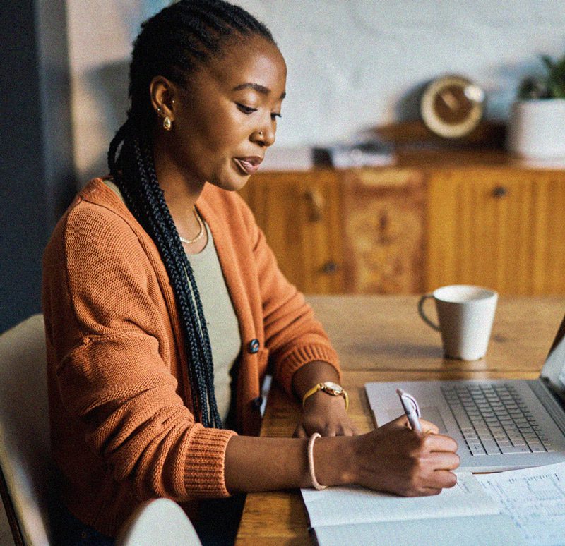 Woman in orange cardigan focusing and working from home.