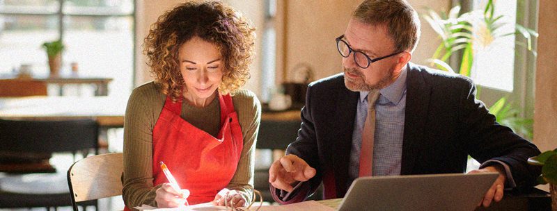 Finance professional and small business owner analyzing finances together at a table in a coffee shop