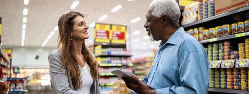 Supplier and grocery store manager shaking hands after a discussion.