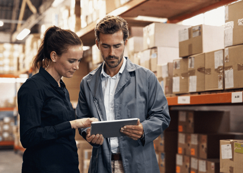 Two people reviewing Ipad in warehouse.