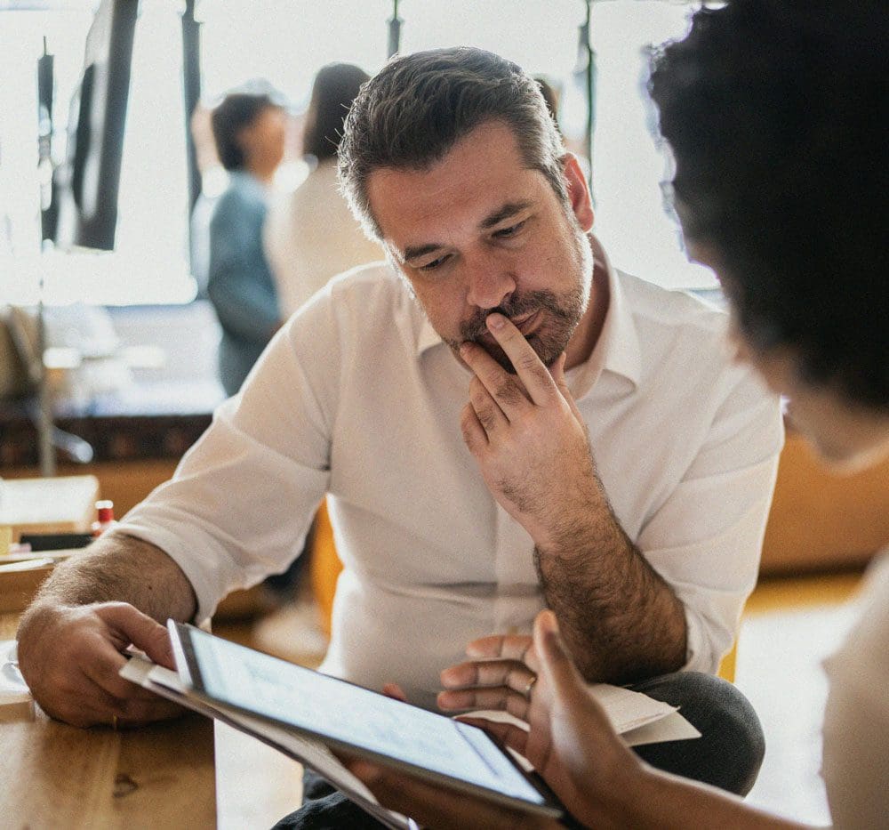 Business professional reviews information on a tablet in the hands of an associate