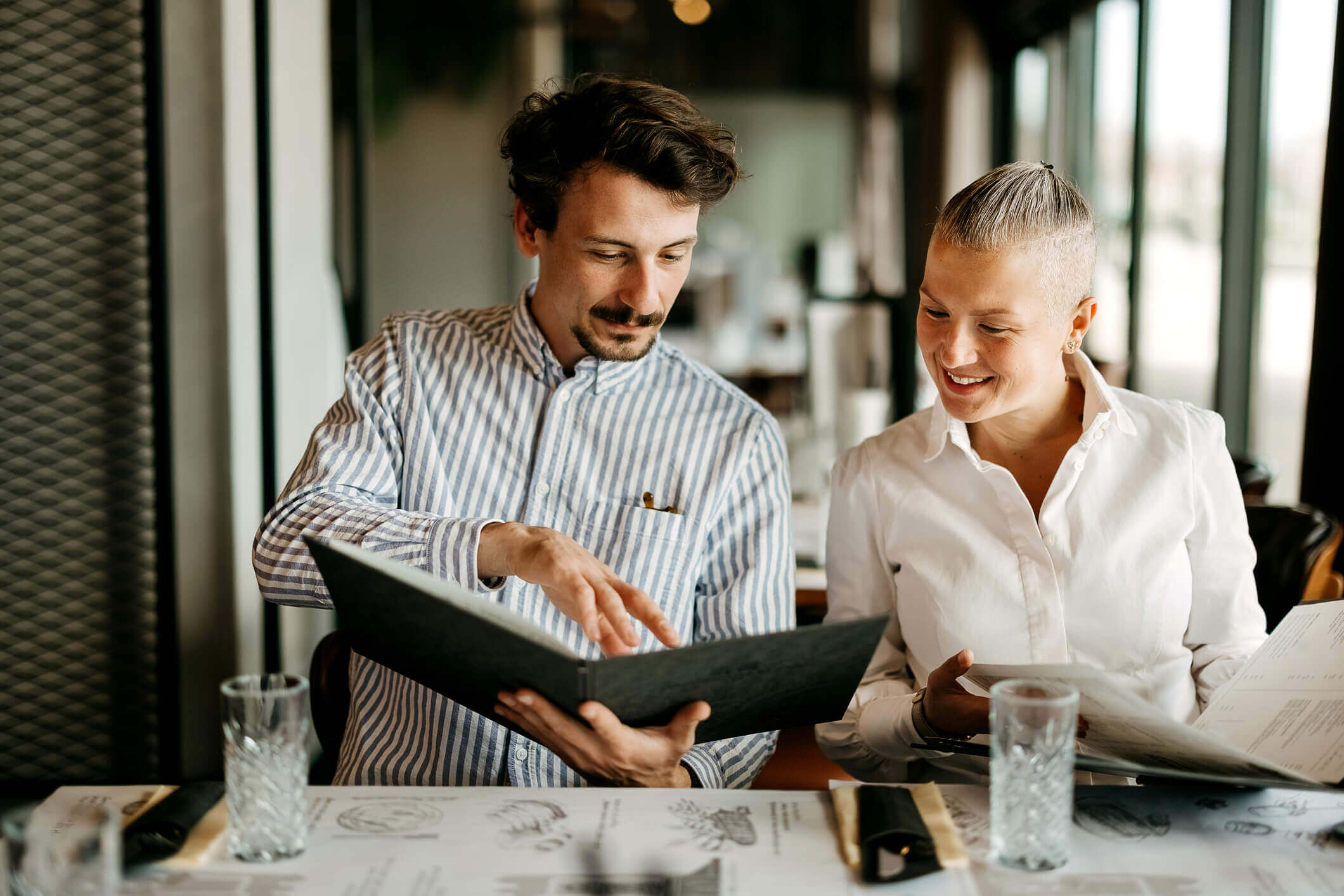 Two people sitting at a table in a restaurant looking at the menu