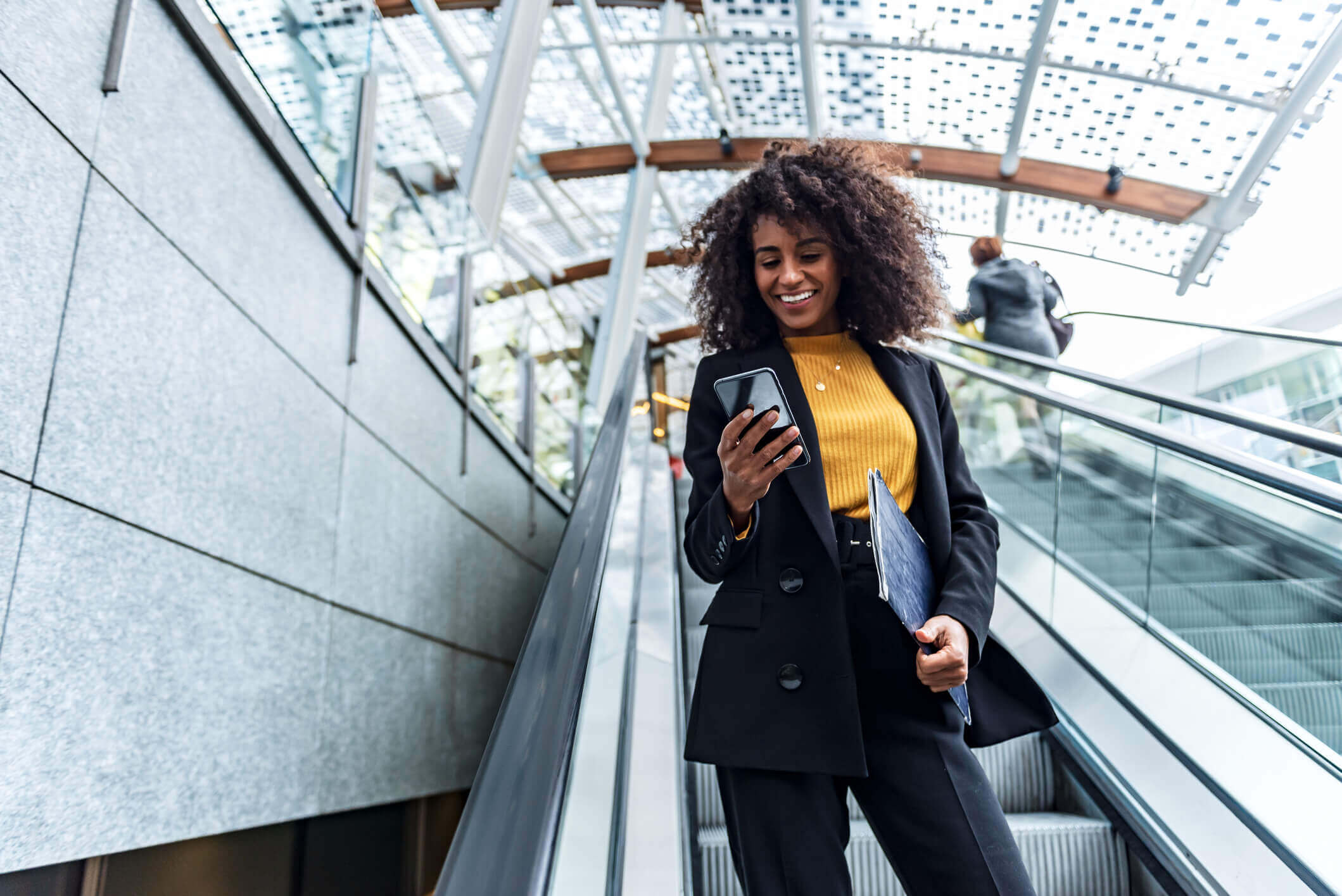 Business woman on an escalator in an airport on her cellphone