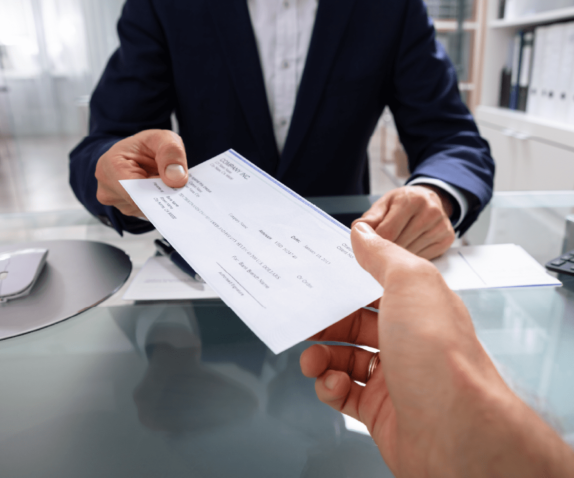 Person handing paycheck to employee via priority payroll & benefits