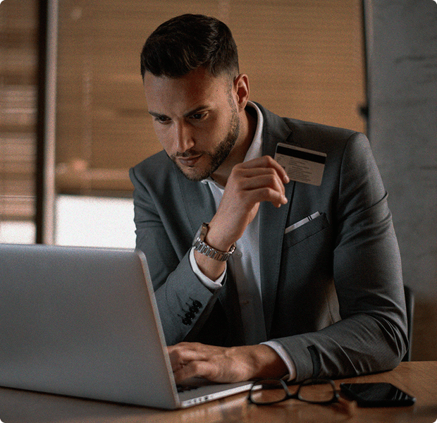 Man in a suite working on a laptop holding credit card