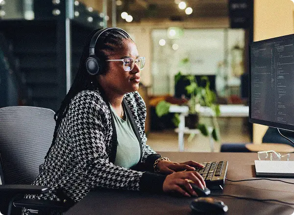 Woman at desk working on laptop with headphones