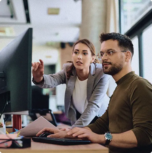 Two people working on a monitor looking at the screen