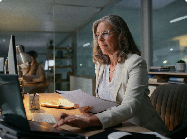 Woman working in an office with lamp on at desk in front of a computer