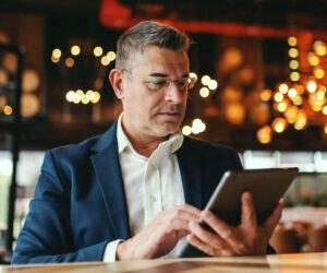 Business professional using a tablet in a modern, warmly lit workspace.