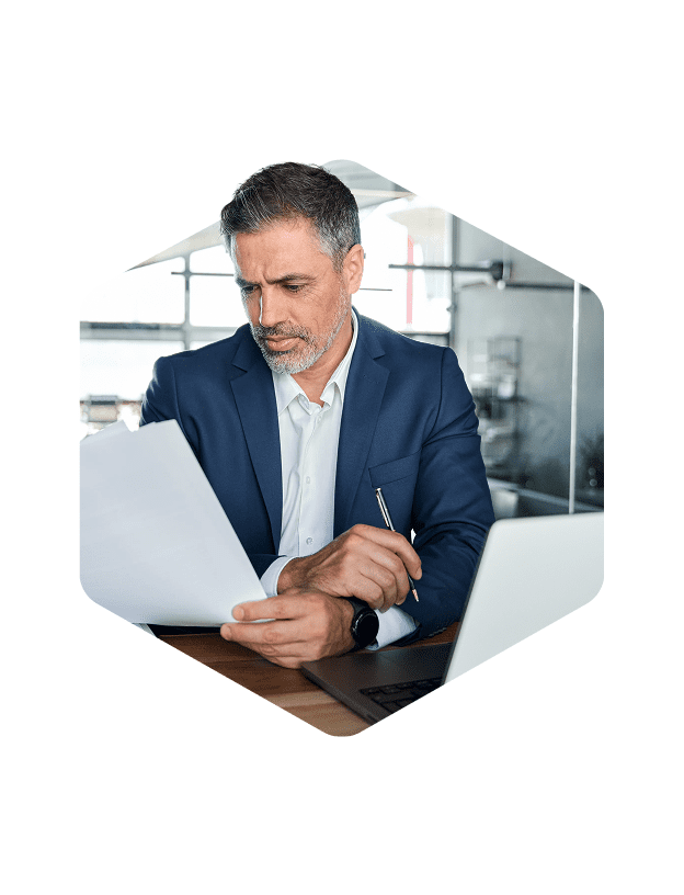 Man working at a desk wearing and looking at a piece of paper