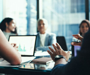 Finance team discussing performance data displayed on a laptop during a meeting.
