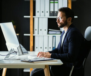 Business professional using a payment management system on a desktop computer in an office.