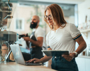 Small business owner managing merchant payment processing on a laptop and tablet.